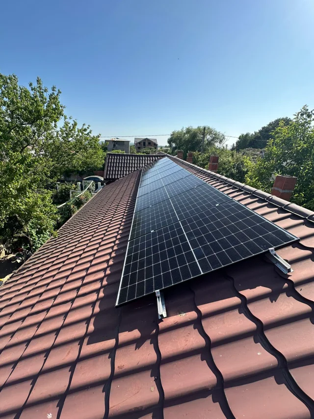 Lucrare SunWatt: șiruri de panouri fotovoltaice pe un acoperiș metalic roșu